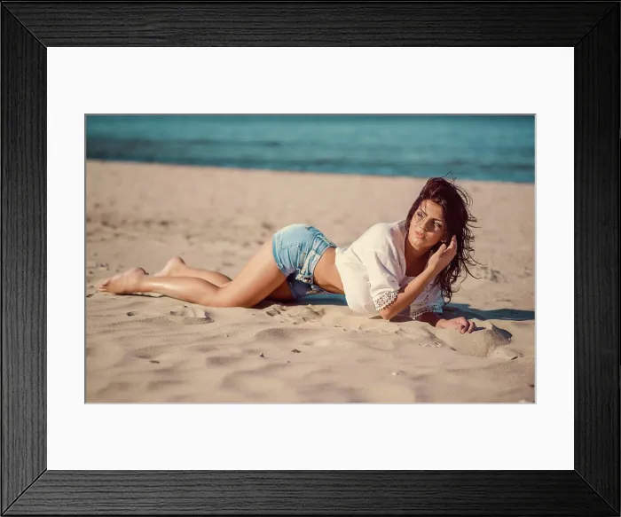 Framed Print : Sexy woman posing on the beach Sexy young woman wearing jeans shorts and white shirt posing on the beach near the sea