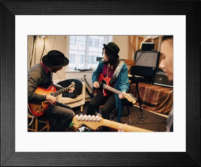 Framed Print : Male and female friends playing guitar while practicing at recording studio Framed Print : Male and female friends playing guitar while practicing at recording studio