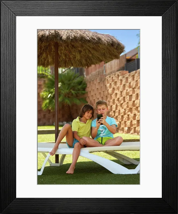 Framed Print : Cheerful boys browsing smartphone on sunbed Framed Print : Cheerful boys browsing smartphone on sunbed
