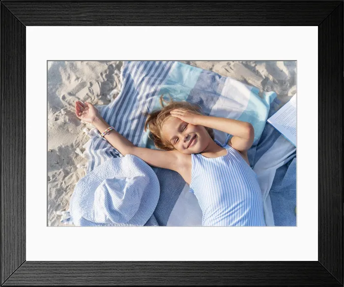 Framed Print : A girl on the beach is resting on a towel and smiling Framed Print : A girl on the beach is resting on a towel and smiling