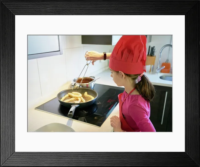 Framed Print : girl makes fritters in the frying pan at home Framed Print : girl makes fritters in the frying pan at home