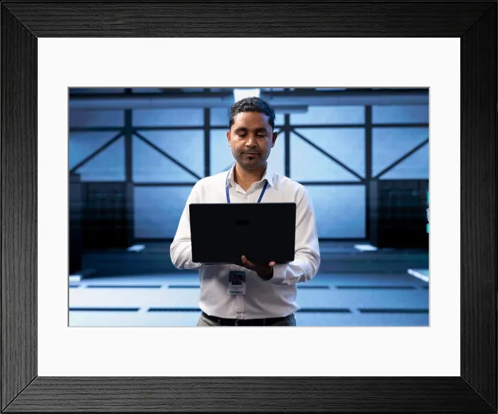 Framed Print : Engineer in server farm checking recovery plan on laptop