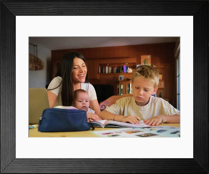 Framed Print : Young boy doing homework with mother and baby boy at home Framed Print : Young boy doing homework with mother and baby boy at home