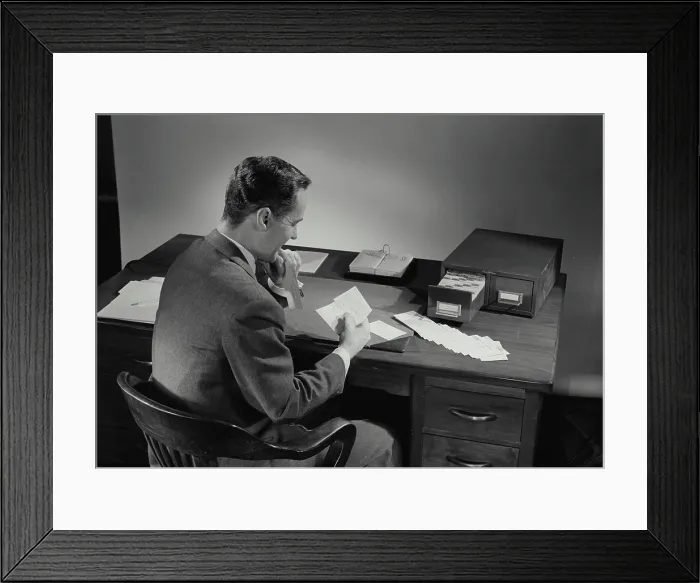 Framed Print : Vintage Photograph. Man in suit sitting at desk covered in papers. Frame 4 Framed Print : Vintage Photograph. Man in suit sitting at desk covered in papers. Frame 4