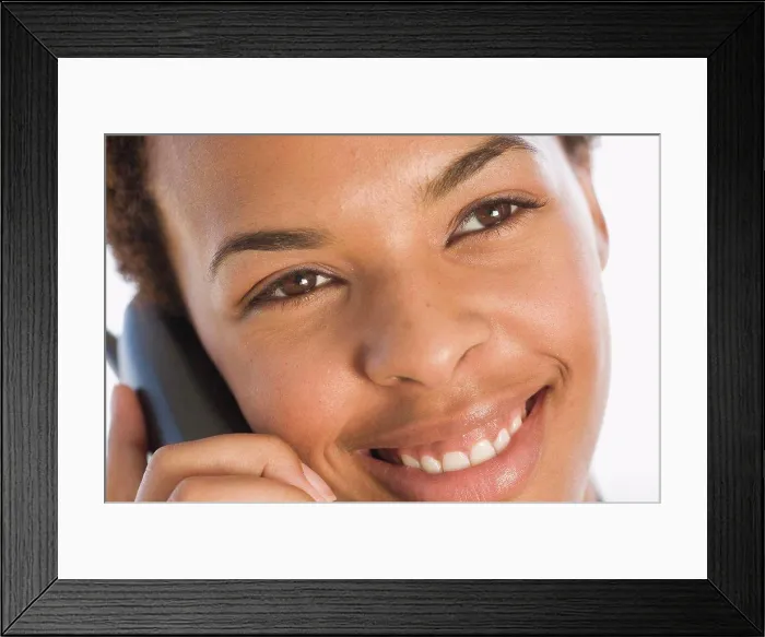 Framed Print : Close-up of a businesswoman talking on a cordless phone and smiling