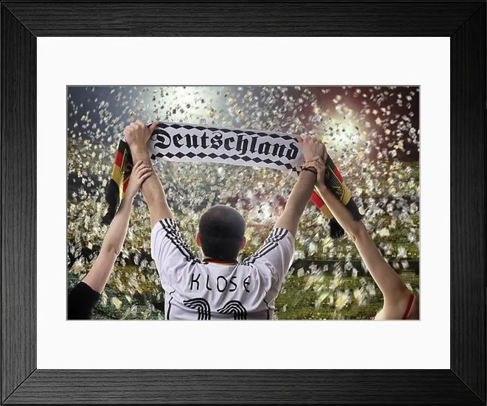 Framed Print : Football fan holding up a German supporters scarf, seen from behind, with confetti in a football stadium Framed Print : Football fan holding up a German supporters scarf, seen from behind, with confetti in a football stadium