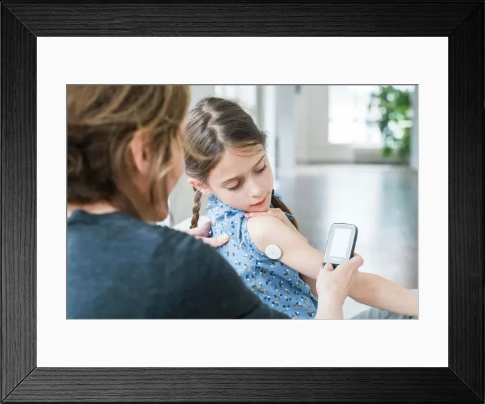 Framed Print : Woman checking blood sugar level (self glycemia) of a diabetic child with FreeStyle Libre ® Framed Print : Woman checking blood sugar level (self glycemia) of a diabetic child with FreeStyle Libre ®