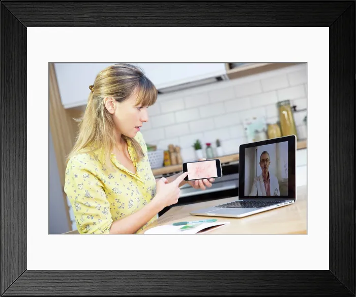 Framed Print : A video consultation between a young woman and her GP for a heat rash that she has taken a photo of using her mobile Framed Print : A video consultation between a young woman and her GP for a heat rash that she has taken a photo of using her mobile