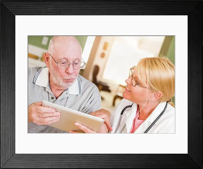 Framed Print : Female doctor or nurse showing senior man touch pad computer at home Framed Print : Female doctor or nurse showing senior man touch pad computer at home