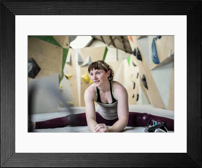 Framed Print : Young female rock climber stretching in climbing gym
