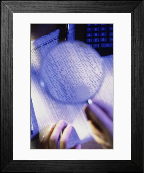 Framed Print : Close-up of a person's hand holding a magnifying glass over a newspaper Framed Print : Close-up of a person's hand holding a magnifying glass over a newspaper