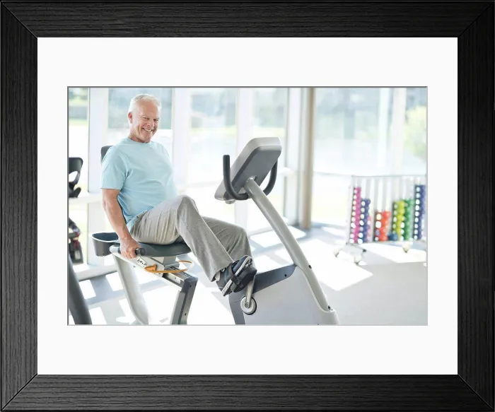 Framed Print : Senior man on static bike in the gym Framed Print : Senior man on static bike in the gym
