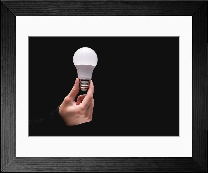Framed Print : light bulb in hand on a black background. Close-up of a woman's hand holding a light bulb. Studio shot Framed Print : light bulb in hand on a black background. Close-up of a woman's hand holding a light bulb. Studio shot