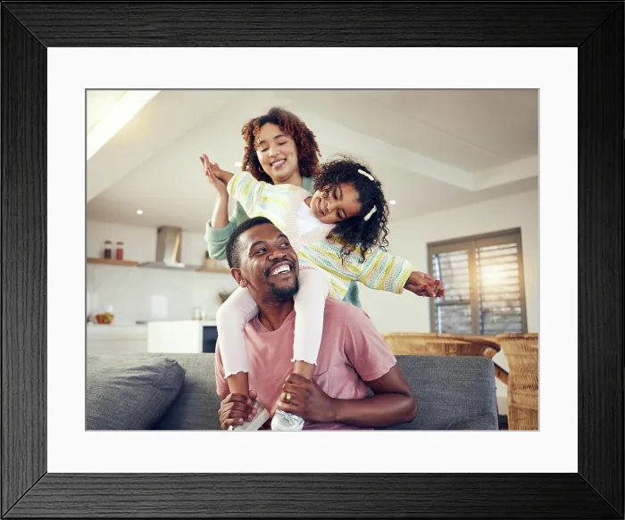 Framed Print : Black family, father and daughter playing with mother on living room sofa together for fun bonding at home Framed Print : Black family, father and daughter playing with mother on living room sofa together for fun bonding at home