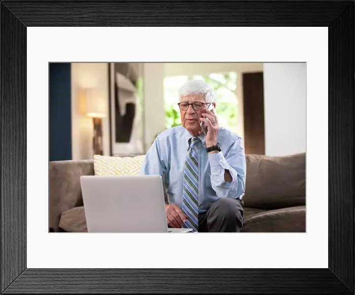 Framed Print : Mature Caucasian Male doctor practicing tele-medicine from his home