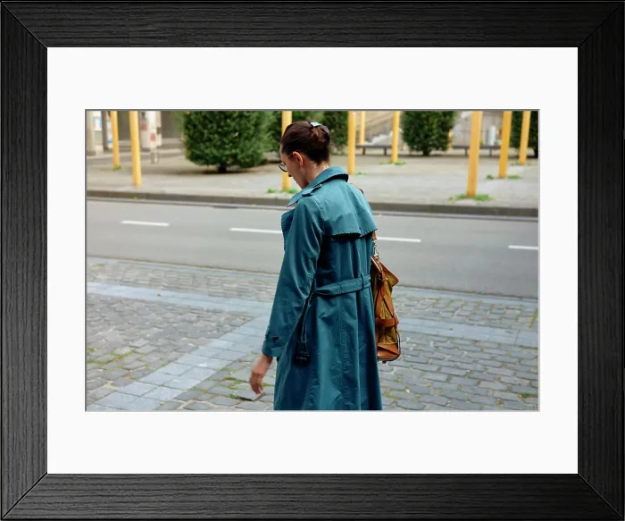Framed Print : Woman in a blue trench coat walking on a city sidewalk with a yellow shoulder bag Framed Print : Woman in a blue trench coat walking on a city sidewalk with a yellow shoulder bag