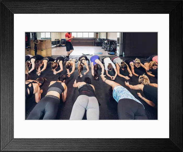 Framed Print : Large group of women training in gym with male trainer, doing push ups