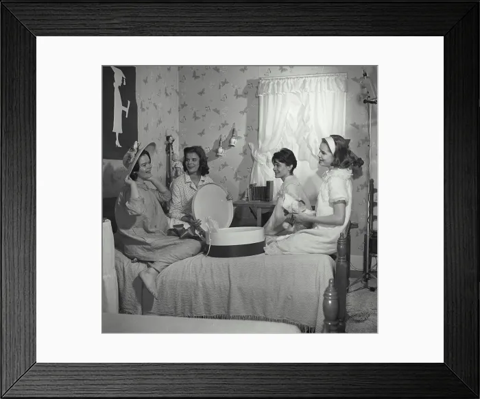 Framed Print : Vintage Photograph. A group of young girls at slumber party trying on floral hat