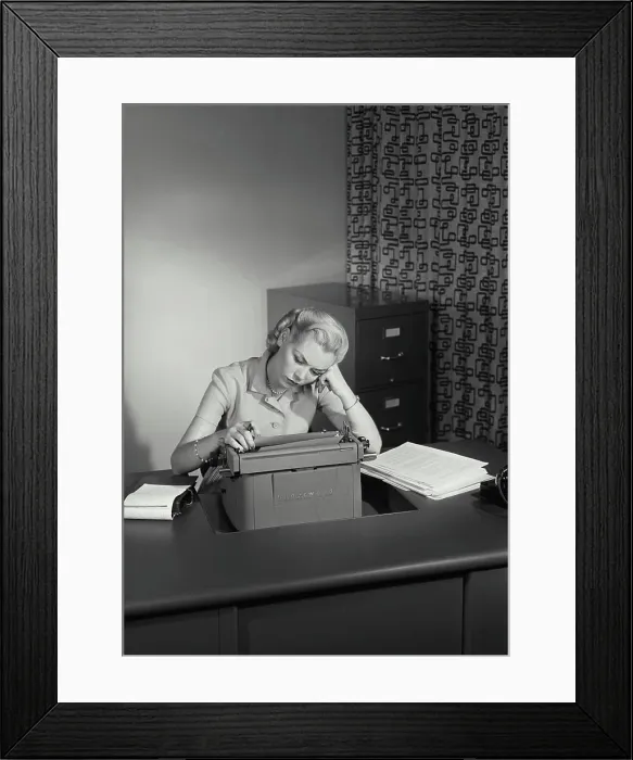 Framed Print : Vintage Photograph. Young woman sitting at office desk with typewriter resting head on hand looking tired Framed Print : Vintage Photograph. Young woman sitting at office desk with typewriter resting head on hand looking tired