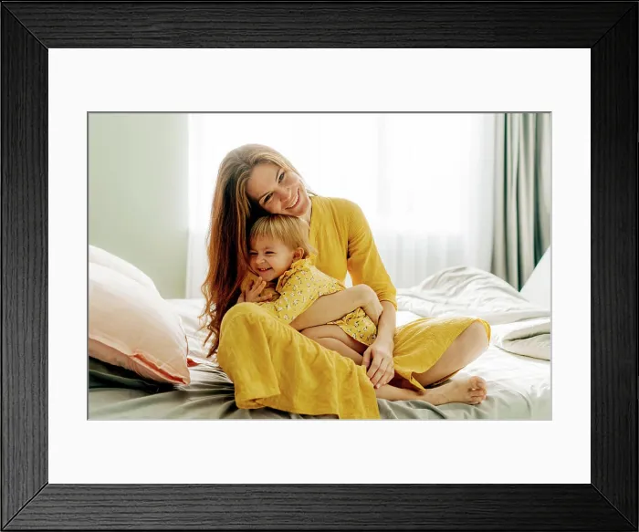 Framed Print : Lachende Mutter, die ihre kleine Tochter umarmt Framed Print : Lachende Mutter, die ihre kleine Tochter umarmt