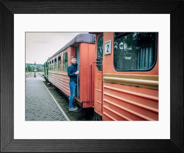 Framed Print : Man stands on the bandwagon of old train of a narrow-gauge railway Framed Print : Man stands on the bandwagon of old train of a narrow-gauge railway