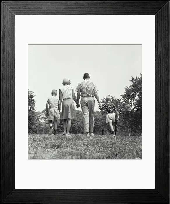 Framed Print : Vintage Photograph. A family group walking holding hands away from camera
