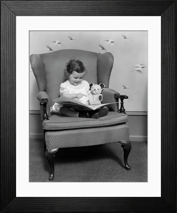 Framed Print : 1930S Little Girl Child In Large Chair With Bear Reading Book Framed Print : 1930S Little Girl Child In Large Chair With Bear Reading Book