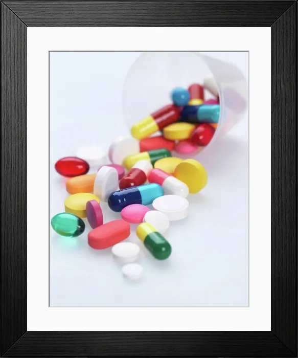 Framed Print : A variety of pills falling out of plastic measuring container
