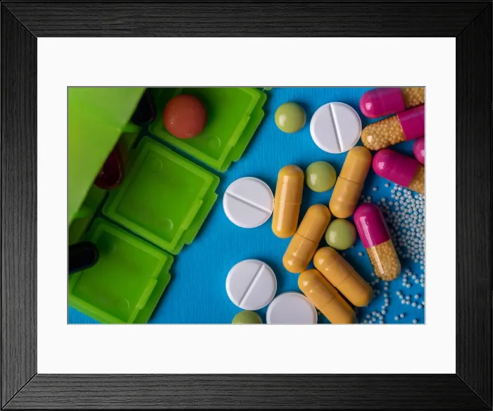 Framed Print : Top view with a green organizer and capsules and multicolored pills