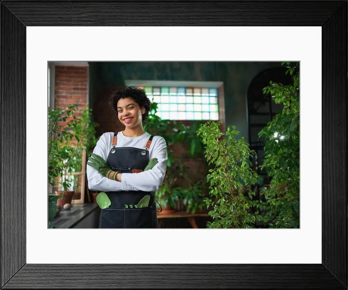 Framed Print : Running of own business. African woman florist wearing apron in botanical store with green plants