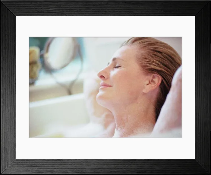 Framed Print : Woman lying with her eyes closed in a bubble bath