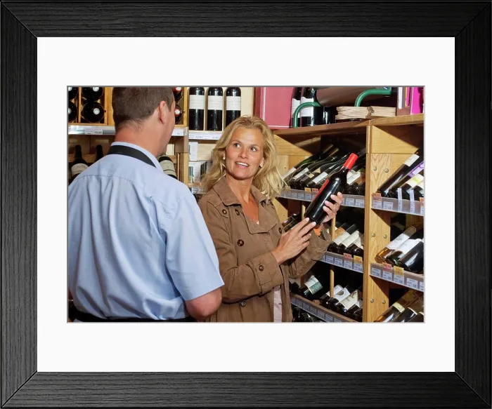 Framed Print : Occidental woman, selecting a bottle of wine Framed Print : Occidental woman, selecting a bottle of wine