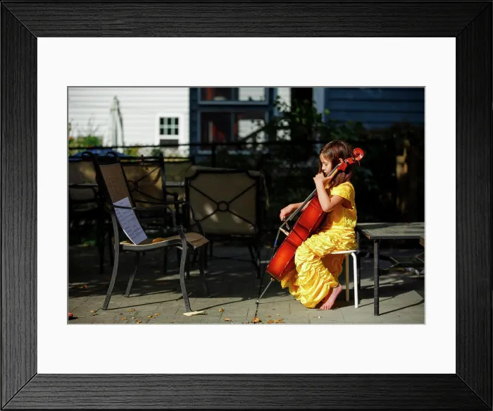 Framed Print : Side-view of focused, barefoot girl playing cello outside in costume Framed Print : Side-view of focused, barefoot girl playing cello outside in costume