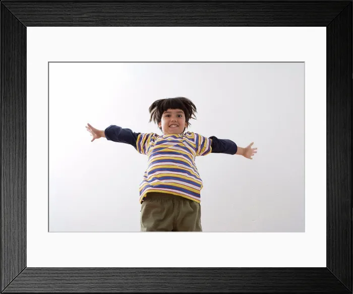 Framed Print : Low angle view of a boy jumping and smiling Framed Print : Low angle view of a boy jumping and smiling