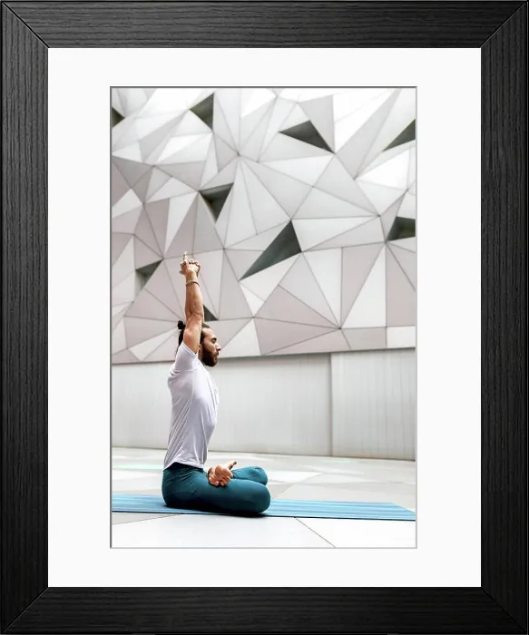 Framed Print : Adult bearded man in sportswear sitting crossed legged and meditating with closed eyes