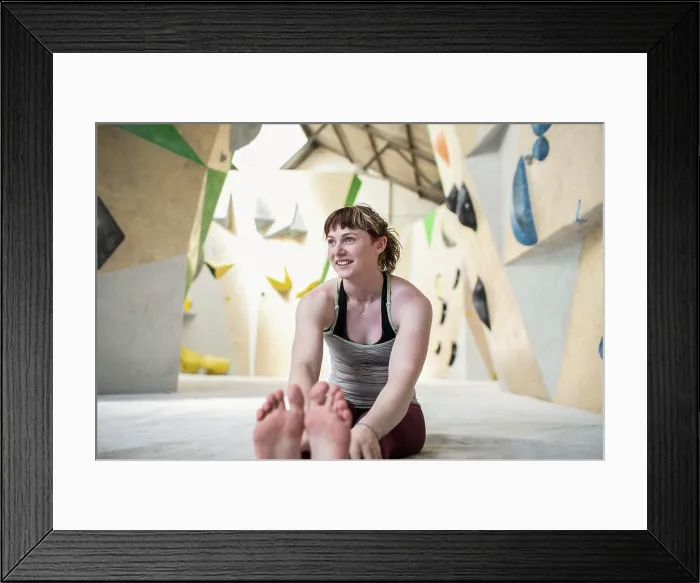 Framed Print : Smiling young woman stretching below climbing wall Framed Print : Smiling young woman stretching below climbing wall
