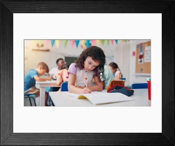 Framed Print : Notebook, education and writing with girl in classroom for child development Framed Print : Notebook, education and writing with girl in classroom for child development
