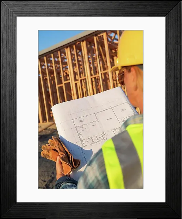 Framed Print : Female construction worker with house plans at construction site