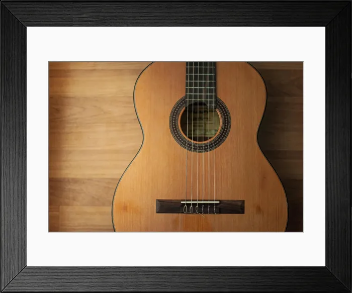 Framed Print : Acoustic guitar resting against a wooden background Framed Print : Acoustic guitar resting against a wooden background