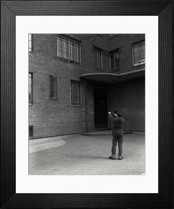Framed Print : Rear view of a boy aiming at windows with a slingshot