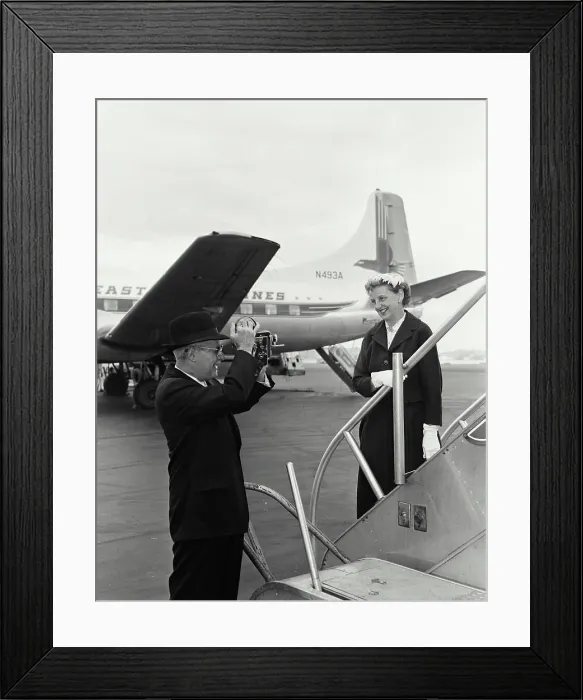 Framed Print : Senior man taking a picture of a senior woman at an airport Framed Print : Senior man taking a picture of a senior woman at an airport