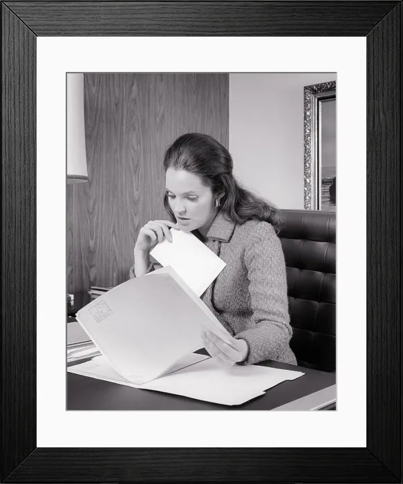 Framed Print : 1970s WOMAN ADMINISTRATOR INTENTLY FOCUSED ON REVIEWING CONTENTS OF A FILE SEATED AT HER DESK - o3331 HAR001 HARS