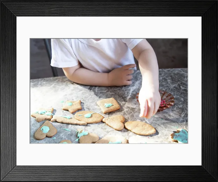 Framed Print : Little boy is decorating ginger cookies on the kitchen Framed Print : Little boy is decorating ginger cookies on the kitchen