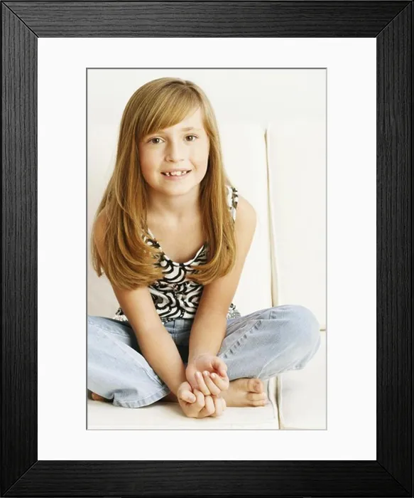 Framed Print : Close-up of a girl sitting on a couch Framed Print : Close-up of a girl sitting on a couch