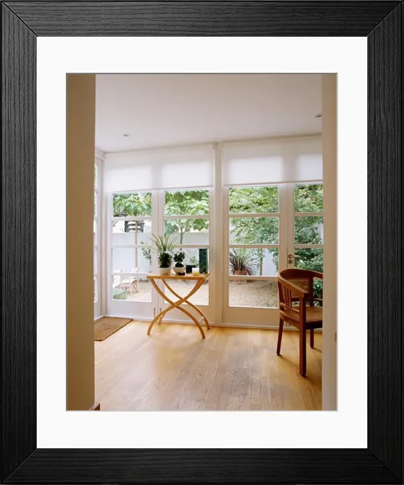 Framed Print : View of patio through glass doors with white blinds in modern livingroom with small table on wooden floor Framed Print : View of patio through glass doors with white blinds in modern livingroom with small table on wooden floor