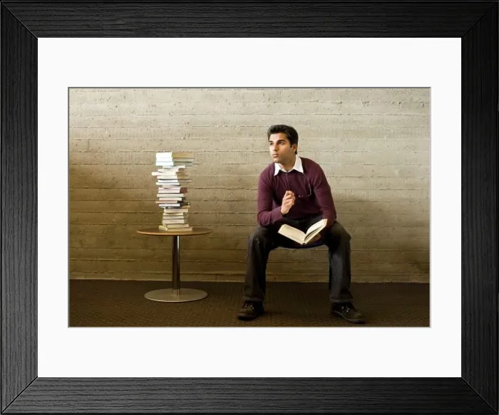 Framed Print : Young man reads and studies in a library Framed Print : Young man reads and studies in a library