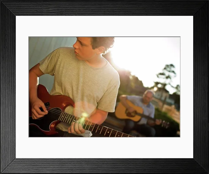 Framed Print : Father and son practicing playing guitar together Framed Print : Father and son practicing playing guitar together