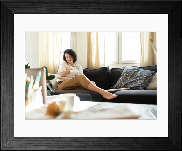 Framed Print : Woman with pillow on sofa near table with brushes and laptop Framed Print : Woman with pillow on sofa near table with brushes and laptop