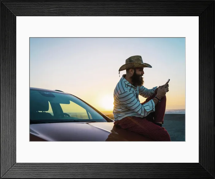 Framed Print : Traveler sitting on car browsing smartphone Framed Print : Traveler sitting on car browsing smartphone