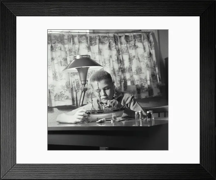 Framed Print : Vintage Photograph. young boy sitting at desk working on building model ship Framed Print : Vintage Photograph. young boy sitting at desk working on building model ship